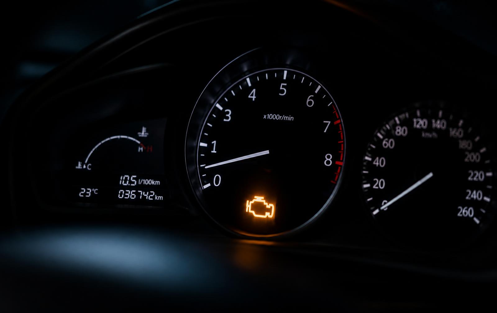 Tablero de un automóvil de noche con la luz de check engine encendida